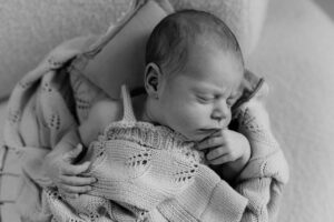 Schlafendes Baby in eine Wolldecke gewickelt im Fotostudio in Hamburg