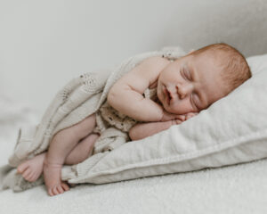 Schlafendes Baby auf einem Kissen kuschelig in eine Decke gewickelt